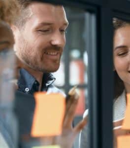 Colleagues working together with wall of orange sticky notes