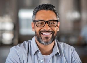Man with glasses and beard smiling at camera