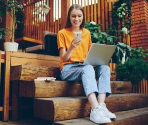 Girl on steps on laptop and cellphone