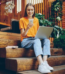 Girl on steps on laptop and cellphone